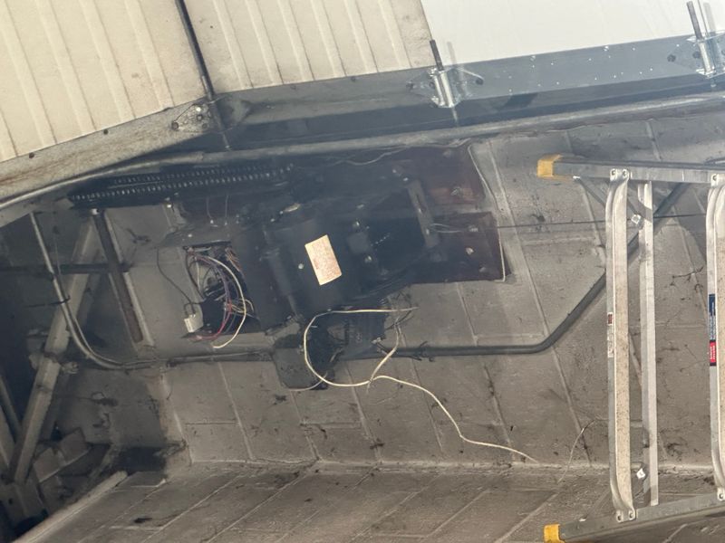 Close-up of commercial garage door opener motor and spring system during repair in MA