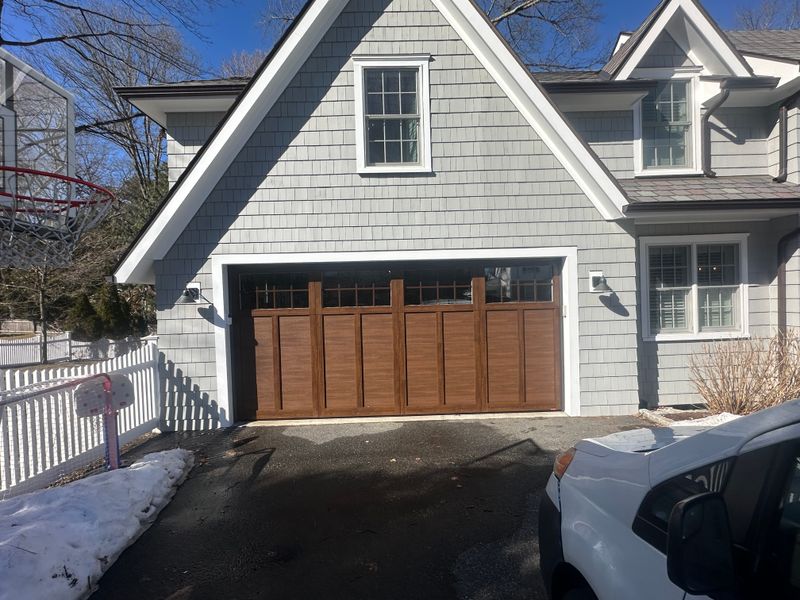 Custom wood craftsman garage door with transom windows on gray shingle home — MA winter